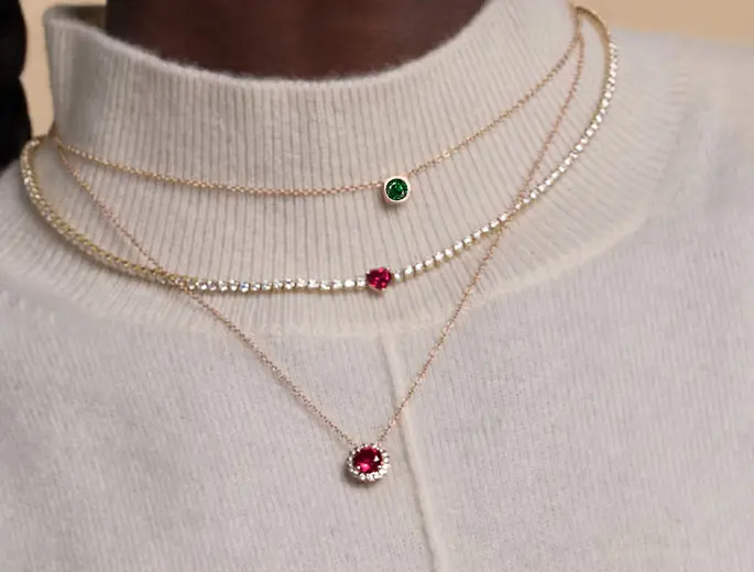 A woman wearing three different types of gemstone necklaces